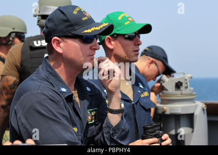 Straße von Hormuz (Jan. 25, 2018) kommandierenden Offizier, Cmdr. Russ Moore, Links, und Leutnant Andrew Archbold stand zusehen, wie die geführte Anti-raketen-Zerstörer USS der Sullivans (DDG68) führt eine Routine Durchfahrt durch die Straße von Hormuz neben MV Cape Ray (T-AKR 9679). Das Sullivans ist in die USA 5 Flotte Bereich der Maßnahmen zur Unterstützung der Marine im Einsatz für die Stabilität und Sicherheit in der Region zu gewährleisten und verbindet das Mittelmeer und den Pazifischen Raum durch den westlichen Indischen Ozean und drei strategischen Punkten ersticken. (U.S. Marine Foto von Leutnant Daphne Weiß/Freigegeben) Stockfoto