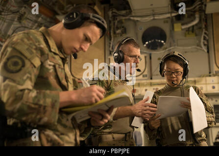 Senior Airman Kyle Caldwell, Flug Medic, Links, Maj Jeffery Carlson, medizinische Crew Director, und Kapitän Isebell Zhang, Flug Krankenschwester, Patient medizinische Berichte an Bord einer C-17 Globemaster III auf dem Weg zur Air Base Ramstein, Deutschland, 21. Juli 2018. Die Flieger der 455th Expeditionary Aeromedical Evacuation Squadron am Flughafen Bagram, Afghanistan, sind damit beauftragt, mit dem Transport von USA und NATO-Partner Service Mitglieder verletzt. (U.S. Air Force Foto von Tech. Sgt. Eugene Crist) Stockfoto