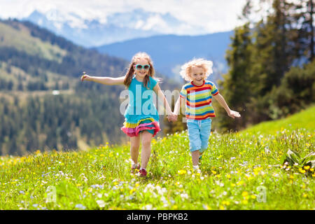 Kinder Wandern in den Alpen. Kinder laufen im Schnee bedeckten Berg in Österreich. Feder für die ganze Familie. Kleinen Jungen und Mädchen auf Wanderung Trail im blühenden Stockfoto