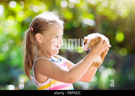 Kinder spielen mit Meerschweinchen. Kinder feed Cavia Tiere. Kleines Mädchen halten und füttern Haustier. Kinder kümmern sich um Haustiere. Preschooler kid Pe Stockfoto