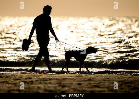 Norderney, Deutschland. 27. Juli, 2018. Ein Mann in der Abendsonne mit seinem Hund am nördlichen Strand von der Insel. Credit: Hauke-Christian Dittrich/dpa/Alamy leben Nachrichten Stockfoto