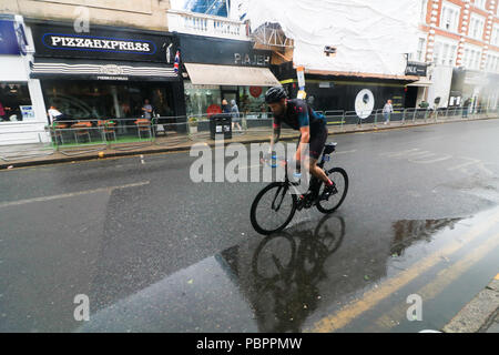 London, Großbritannien. 29. Juli 2018. Radfahrer durch Wimbledon Village in der aufsichtsrechtlichen London Surrey 100 Classic Event in nassen Bedingungen wie die Regenzeit, unten zu kommen. Die aufsichtsrechtlichen Fahrt London-Surrey 100 in seiner sechsten Jahr feiert das Vermächtnis für die London 2012 die Olympischen und Paralympischen Spiele erstellt Radfahren und folgt einer 100km Route auf geschlossenen Straßen durch das Kapital und in die Landschaft von Surrey Credit: Amer ghazzal/Alamy leben Nachrichten Stockfoto