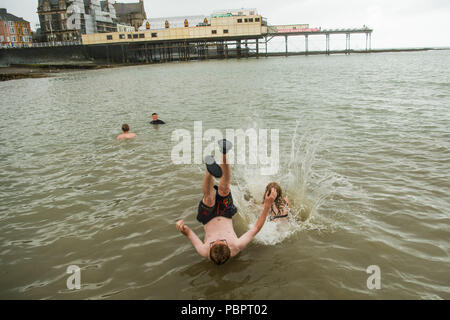 Aberystwyth Wales UK, Sonntag, den 29. Juli 2018 UK Wetter: Jugendliche immer noch Spaß haben einen Sprung von der Anlegestelle, obwohl es ein grau, nass und bedeckt Sonntag am Meer in Aberystwyth auf der West Wales Küste der langen Hitzewelle schließlich bricht mit Gewitter und sintflutartige Regenfälle über viel des Landes Foto: Keith Morris/Alamy leben Nachrichten Stockfoto