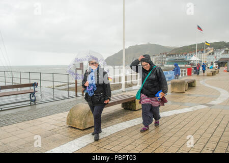 Aberystwyth Wales UK, Sonntag, den 29. Juli 2018 UK Wetter: Leute auf einem grauen, nassen und bedeckt Sonntag getränkt am Meer in Aberystwyth auf der West Wales Küste. Die langen Hitzewelle bricht schließlich unten mit Gewitter und sintflutartige Regenfälle über viel des Landes Foto: Keith Morris/Alamy leben Nachrichten Stockfoto