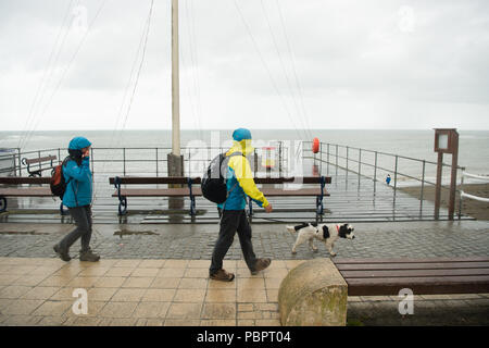 Aberystwyth Wales UK, Sonntag, den 29. Juli 2018 UK Wetter: Leute auf einem grauen, nassen und bedeckt Sonntag getränkt am Meer in Aberystwyth auf der West Wales Küste. Die langen Hitzewelle bricht schließlich unten mit Gewitter und sintflutartige Regenfälle über viel des Landes Foto: Keith Morris/Alamy leben Nachrichten Stockfoto