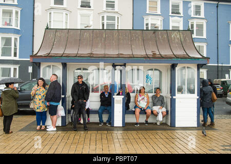 Aberystwyth Wales UK, Sonntag, den 29. Juli 2018 UK Wetter: Leute auf einem grauen, nassen und bedeckt Sonntag getränkt am Meer in Aberystwyth auf der West Wales Küste. Die langen Hitzewelle bricht schließlich unten mit Gewitter und sintflutartige Regenfälle über viel des Landes Foto: Keith Morris/Alamy leben Nachrichten Stockfoto