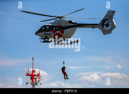 Wilhelmshaven, Deutschland. 29. Juli, 2018. Ein Mensch, der mit einem Seil von einem Hubschrauber auf die Rettung cruiser Hannes Glogner während einer Training Mission der Deutschen Gesellschaft zur Rettung Schiffbrüchiger (DGzRS), die in der Bucht von Jadebusen abgesenkt. Credit: mohssen Assanimoghaddam/dpa/Alamy leben Nachrichten Stockfoto