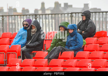 Dorchester, Dorset, Großbritannien. 29. Juli 2018. UK Wetter. Specators Nachbearbeitung vor dem nassen Bedingungen, wie sie im Finale der Weymouth Volleyball Klassiker am Strand beobachten von Weymouth in Dorset an trüben bedeckt und showery Nachmittag - Foto: Graham Jagd Alamy Leben Nachrichten. Stockfoto