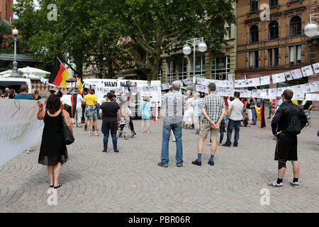 Wiesbaden, Deutschland. 29. Juli 2018. Rechtsradikale Demonstranten hören den Reden. Rechtsextreme Demonstranten der Hand in Hand-Gegen die Gewalt in unseren Strasen (Hand in Hand - gegen Gewalt auf unseren Straßen) Bewegung statt einer regierungsfeindlichen Kundgebung in Wiesbaden. Dieser Protest war unter dem Vorwand, eine Mahnwache für den Jugendlichen Susanna F, der angeblich von einem Flüchtling in Wiesbaden getötet wurde. Die Kundgebung wurde von mehreren Anti-government Referenten, die forderte, dass die Regierung zum Rücktritt gerichtet. Stockfoto