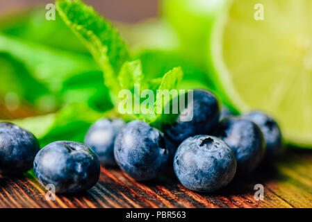 Frische Heidelbeeren und die Hälfte der Limette und Minze auf Hintergrund. Zutaten für die Vorbereitung der Reinigung Wasser. Stockfoto