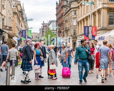 Die Menschen gekleidet für eine Hochzeit mit Männer in Kilts anhalten, um Hallo zu sagen und Begrüßung in einer belebten Straße, Buchanan Street, Glasgow, Schottland, Großbritannien Stockfoto