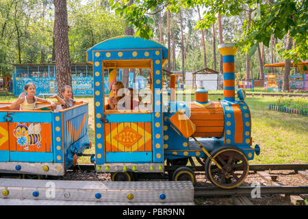 Vier kleine Kinder sind Reiten auf der Bahn in den Park. Stockfoto