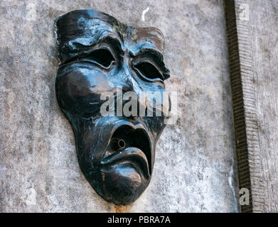 Nahaufnahme von Fringe symbol Komödie die Maske des traurigen Gesicht auf Gut Kopf Street Fountain außerhalb Fringe Box Office, Royal Mile, Edinburgh, Schottland, Großbritannien Stockfoto