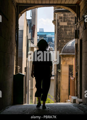 Silhouette einer Frau zu Fuß durch alte Baugruppe schließen, die Royal Mile, Edinburgh, Schottland, Großbritannien im Sommer Stockfoto