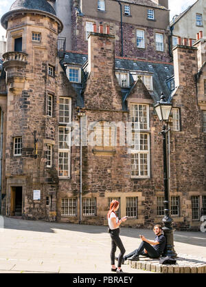 Junges Paar durch altmodische Lamp Post entspannen auf Handys, Makar's Court, Writer's Museum, Edinburgh, Schottland, Großbritannien Stockfoto