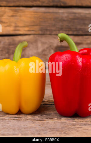 Fröhlich bunte Paprika auf Holz. Gelbe und rote Paprikaschoten mit Tau. Stockfoto