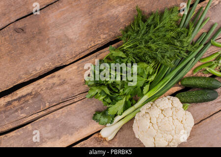 Gemüse liegen auf dem Tisch. Bereit für das Kochen frischer Sommersalat. Ansicht von oben, alte vintage Holztisch Hintergrund. Stockfoto