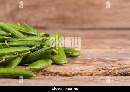 Pea pods und Copyspace. Close Up. Rustikalen Holztisch Hintergrund. Stockfoto