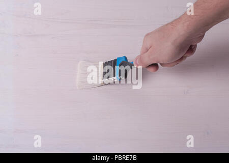 Pinsel in der hand und Malen weiße Farbe auf dem Holz- Light Board. Stockfoto