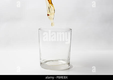 Whiskey Gießen im leeren Glas auf weißem Hintergrund Stockfoto