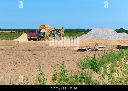 Lkw und Bagger neben einem Haufen Sand, Quarzsand Bergbau Stockfoto