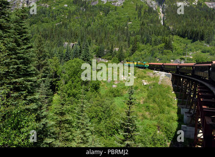 Ein Zug Motor zieht vintage Wagen über einen Bock Brücke auf dem Weg von Skagway, Alaska auf den Gipfel des White Pass - ein 2.885 Fuß Höhe Stockfoto