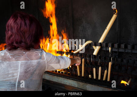 Eine Frau legt ein Votiv Kerzen in den Scheiterhaufen als Erfüllung der Gelübde zu Unserer Lieben Frau von Fatima Portugal zu brennen. Stockfoto