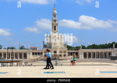 Zwei Polizisten zu Fuß über das Gelände des Heiligtums von Fatima in Portugal mit der Basilika Unserer Lieben Frau im Hintergrund Stockfoto