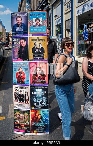 Eine junge Frau in Sonnenbrille zu Fuß durch Edinburgh Fringe Plakate auf George IV Bridge in Edinburgh, Schottland, Großbritannien. Stockfoto