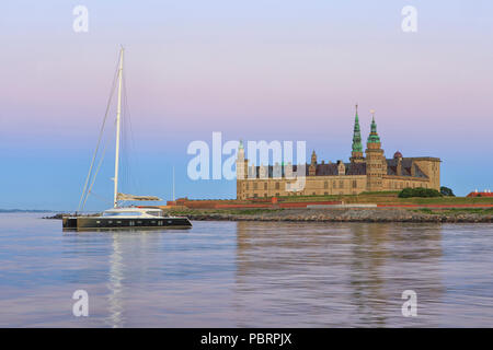 Ein Katamaran für Anker auf Schloss Kronborg (UNESCO Welterbe seit 2000) in der Abenddämmerung in Helsingor, Dänemark Stockfoto