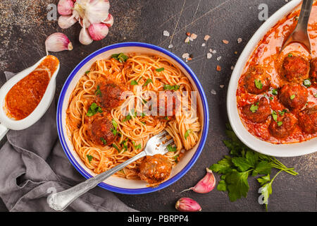 Spaghetti mit Hackbällchen in Tomatensauce mit Petersilie und Knoblauch in weiße Platte, Ansicht von oben, dunklen Hintergrund. Stockfoto