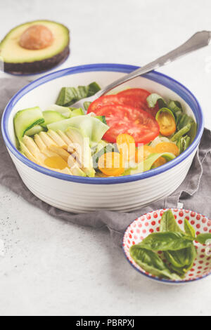 Grüne Zucchini nudeln Salat mit Tomaten, Avocado und Basilikum. Gesund vegan Zucchini Pasta. Saubere Konzept essen. Stockfoto