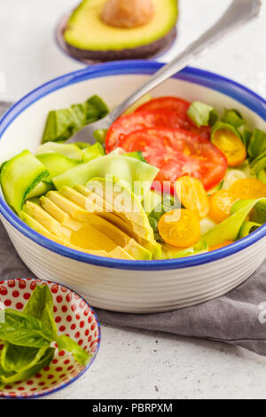 Grüne Zucchini nudeln Salat mit Tomaten, Avocado und Basilikum. Gesund vegan Zucchini Pasta. Saubere Konzept essen. Stockfoto