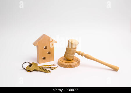 Holz- Haus mit Schlüssel und ein Richter Hammer auf einem weißen Hintergrund. Das Konzept der Versuch eines Mehrfamilienhauses. Die Beschlagnahme von Eigentum. R Stockfoto