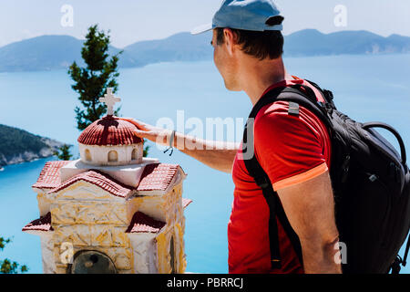 Männliche touristische berührt, nachdenklich zu kleinen griechischen Heiligtum Proskinitari, Griechenland. Herrlichen Blick aufs Meer im Hintergrund Stockfoto