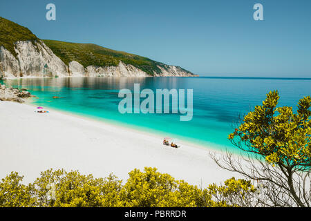 Erstaunlich Fteri Beach Lagoon, Kefalonia Kefalonia, Griechenland. Touristen unter dem Dach in der Nähe von blauen Smaragd türkis Meer Wasser entspannen. Weißen Felsen im Hintergrund Stockfoto