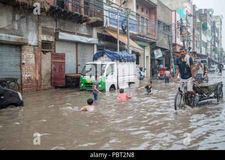 Kinder spielen im Wasser überflutete Straßen nach dem Regen in New Delhi, Indien. Stockfoto