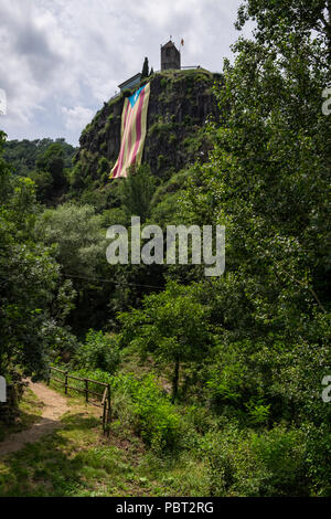 Suchen bis zu Castellfollit de la Roca auf dem Gipfel des hohen Basaltfelsen, rock Escarpment, mit einem enormen katalanischen Unabhängigkeit Flagge nach unten hängen Stockfoto