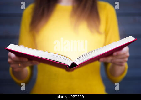 Licht aus Buch in die Hände der Frau. Konzept der Weisheit, Religion, Lesen, Fantasie, Wissen Stockfoto