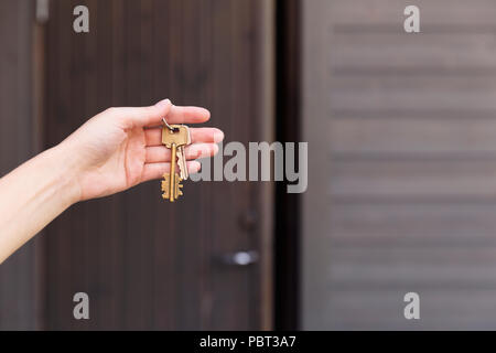 Haus Schlüssel in der Frau die Hand vor der Tür. Erwerb von Immobilien- und Sicherheitskonzept Stockfoto