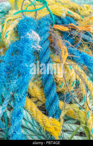 Farbenfroher Haufen alter und ausgefranster Kunststoffseile und Netting zum Angeln. Nahaufnahme des Seils. Stockfoto