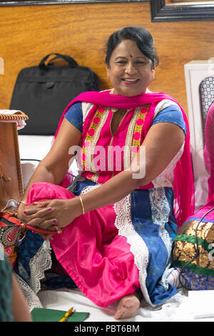Porträt eines lächelnden im mittleren Alter Hindu Frau an einem Service in einem Tempel in Queens, New York City sitzt. Stockfoto