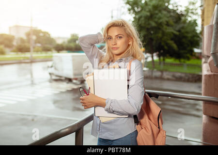 Leidenschaftlich gerne schöne junge Mädchen und lächelnd Stapel Bücher in der Nähe von Campus lifestyle Positivität akademischer Abschluss Universität sch stehend Stockfoto