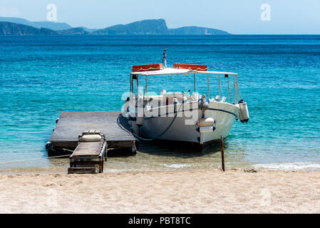 Kleines Boot angedockt an der kleinen Pier am Strand Stockfoto