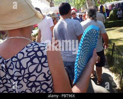 Frau auffächern, selbst mit einem blauen folding Fan wie Sie geht um ein Markt im Süden Frankreichs Stockfoto