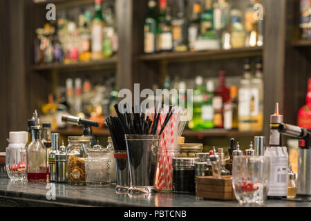 Professionelle cocktail Werkzeuge und Zutaten in Glasflaschen und Gläser für kreative moderne modische Cocktails auf hölzernen Tresen. Stockfoto