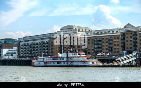 Die Dixie Königin, eine Nachbildung aus dem 19. Jahrhundert Tretboote vermietet als Party Boot, außerhalb Butlers Wharf, ehemalige Lagerhaus jetzt Luxus Wohnungen liegt, Stockfoto