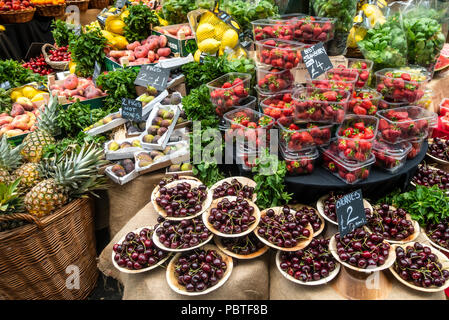 Eine Auswahl an Obst, Feigen, Kirschen, Erdbeeren, Pfirsiche, Nektarinen, Zitronen und Kräutern auf Verkauf im berühmten und historischen Borough Market, London. Stockfoto