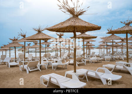 Wicker Sonnenschirme mit chaiselongue am Strand Stockfoto