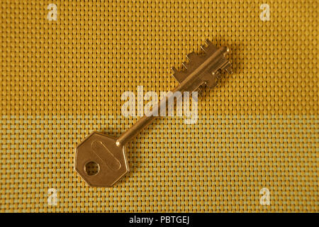 Goldene Schlüssel auf zwei Farben gewebt gelb Textil. Konzeptionelle Schlüssel als Symbol für Acces, das Eigentum oder die Sicherheit. Kostenlose Kopie. Stockfoto